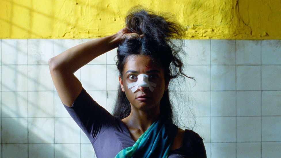 A still of Radhika Apte holding her hair up, with a bandaged nose, in Sister Midnight (Credit: Altitude)