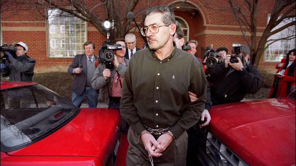 Aldrich Ames being arrested in handcuffs, with members of the press taking photos of him from behind (Credit: Getty Images)