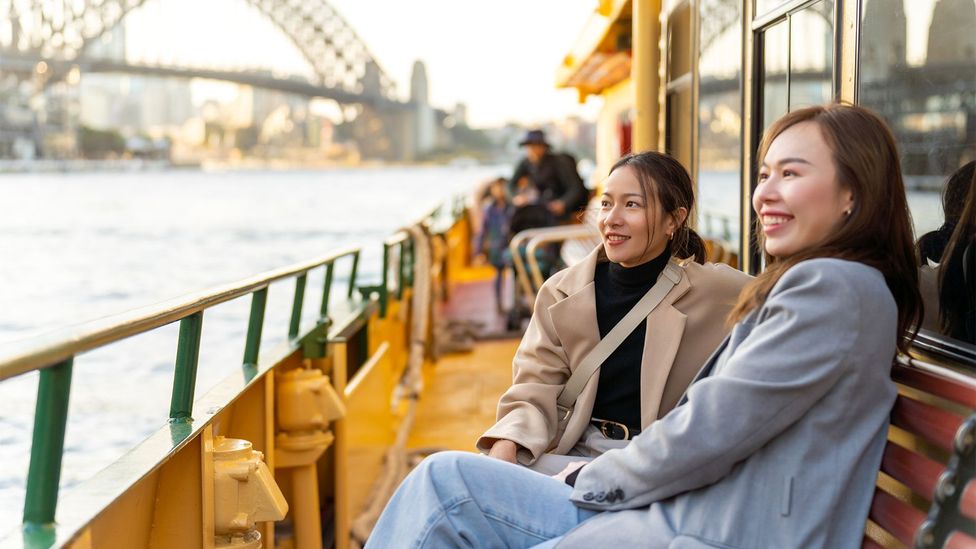 Two female friends travel on ferry boat crossing Sydney harbour in Australia (Credit: Getty Images)