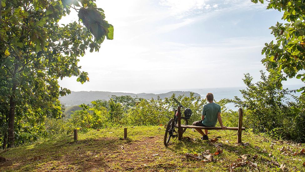 Mountain biker relaxes on wooden bench in Panama with ocean in the distance (Credit: Getty Images)