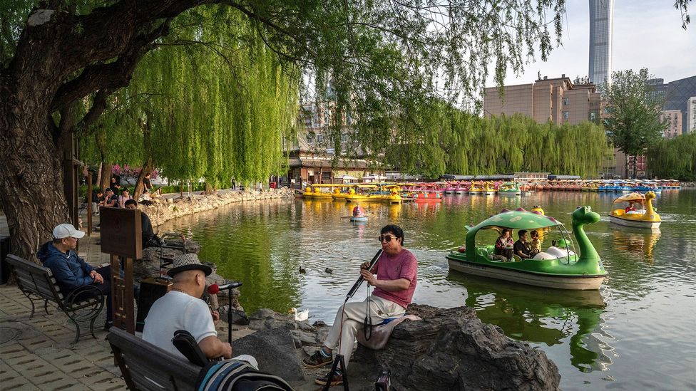 Men play music as a family ride in a boat at a local park in Beijing, China (Credit: Getty Images)