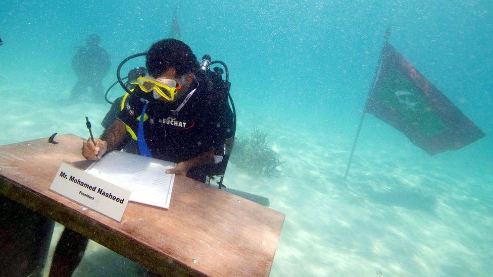 The former president of the Maldives signs a document in scuba gear, underwater (Credit: Alamy)