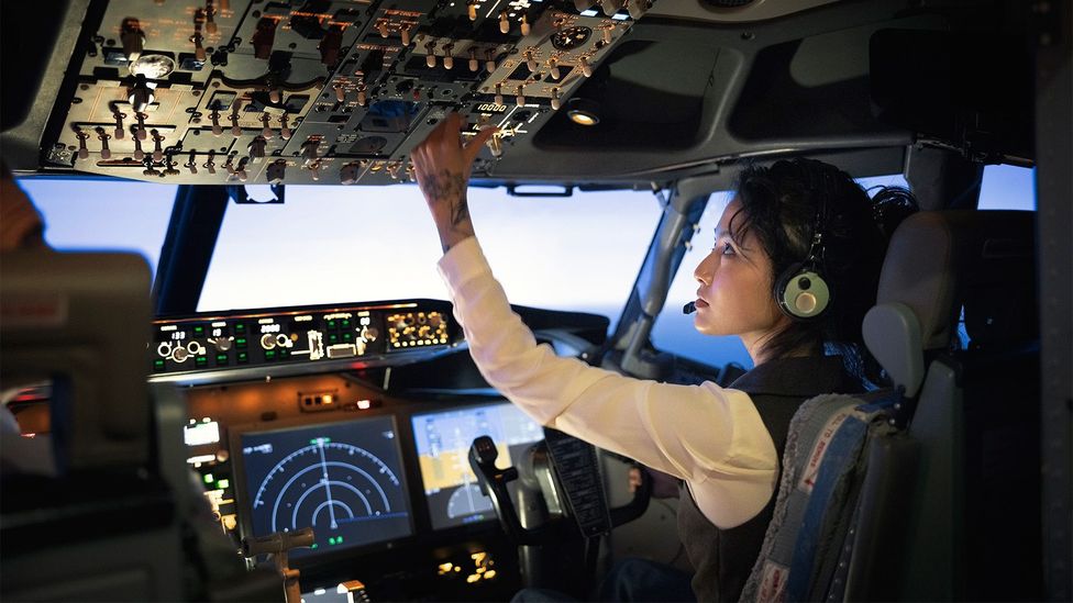 Female pilot adjusting switches on the control panel while sitting inside cockpit (Credit: Getty Images)