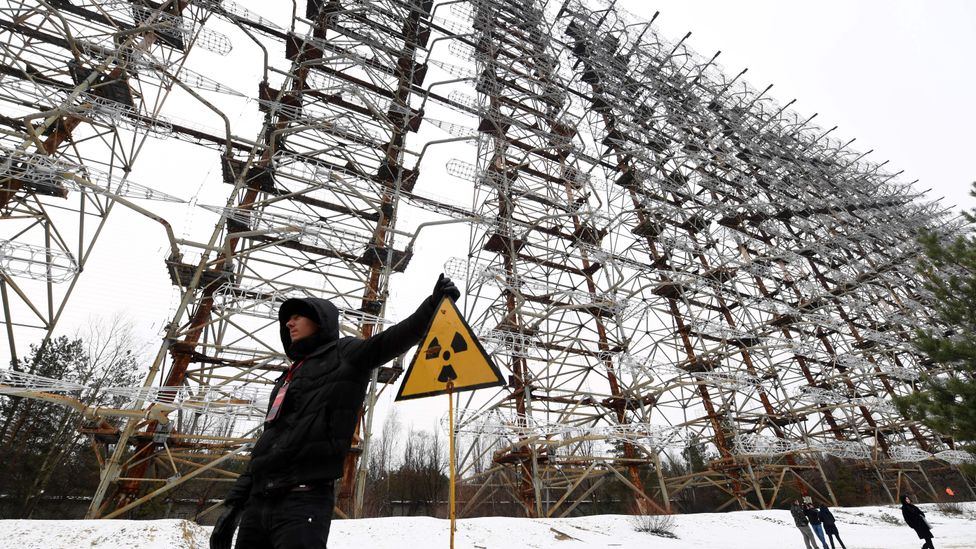 A figure stands by a metal array and radioactivity warning sign (Credit: Getty Images)