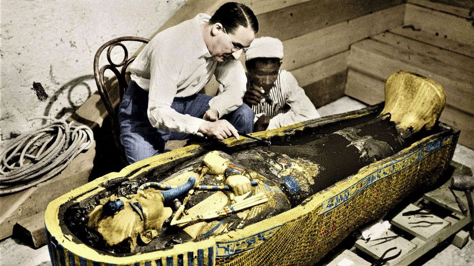 Howard Carter and his assistant crouching by sarcophagus (Credit: Alamy)