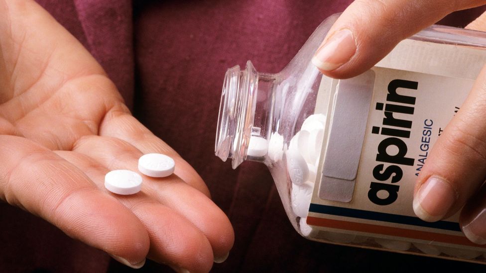 A close up of someone pouring two tablets from a bottle of aspirin (Credit: Getty Images)