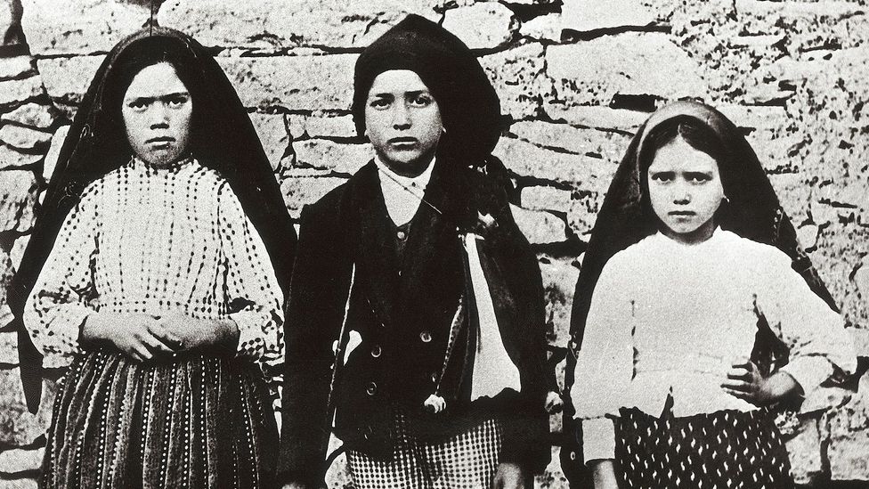 A black-and-white photograph of three young girls stood against a dry stone wall (Credit: Getty Images)