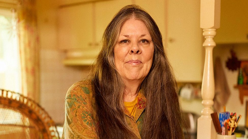 Loreen Willemberg, a woman with long hair, sits in a kitchen (Credit: Ari Michelson/ AUGUST)