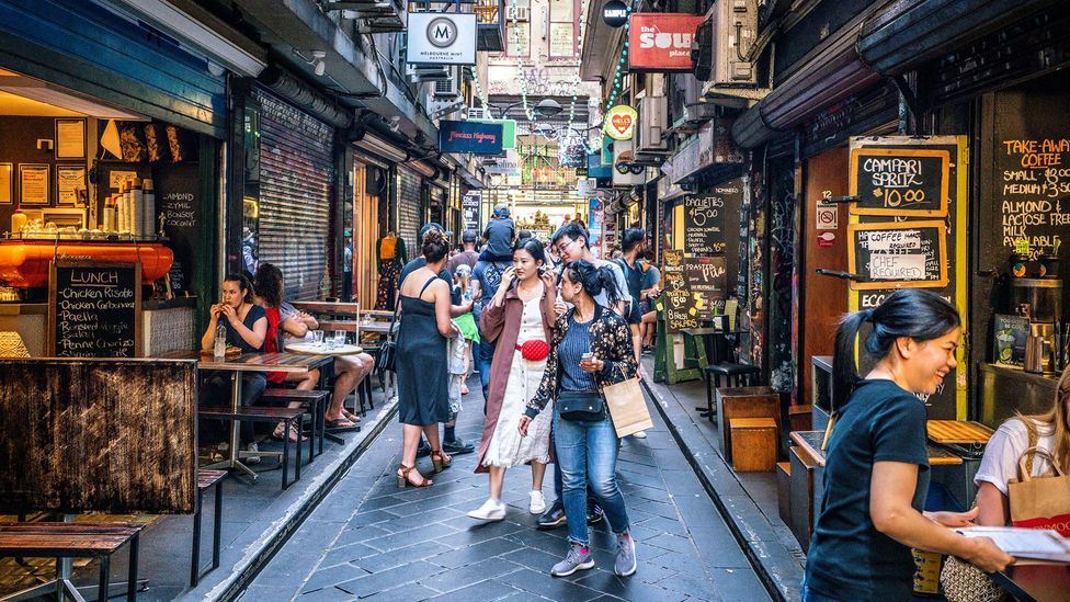 People walk through a cafe-lined laneway (Credit: Getty Images)