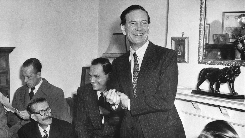 A black-and-white photo of Kim Philby in a suit speaking to a room of men (Credit: Getty Images)