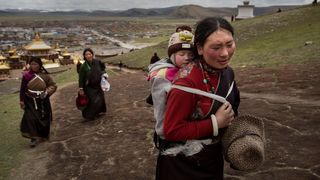 A Tibetan woman carrying her baby on her back (Credit: Getty Images)