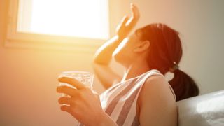 Woman in hot room with glass of water (Credit: Skaman306/Getty Images)