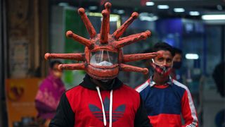 A man wearing a helmet shaped like a virus (Credit: Getty Images)