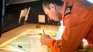 A sailor annotates a paper chart on a ship bridge (Credit: UK Hydrographic Office)
